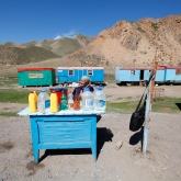 Naryn, Kirghizstan, Mai 2014. Nous revenons du caravansérail de Tash-Rabbat, qui m’a laissé étourdie de joie. Le chauffeur, qui maîtrise autant l’anglais que moi le kirghize, s’arrête. Des deux côtés de la route, d’anciens wagons de chemin de fer transformés en caravanes. Une femme vend des bouteilles d’occasion, remplies de je ne sais quoi. De l’essence, ai-je d’abord pensé, me remémorant les bidons d’essence de Bali et Java. Une heure après, je finis par comprendre que nous avons acheté du lait fermenté. J’y trempe à peine mes lèvres. J’ai encore ce goût sûr sur la langue, apaisé pour le souvenir de cette nomade joviale, qui, elle, n’a pas du tout l’impression d’être l’une des dernières représentantes du monde d’hier. De plus en plus de camionneurs Chinois passent sur cette route, et c’est probablement le plus important.